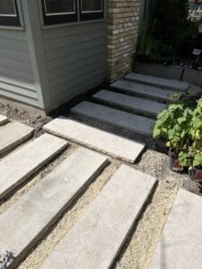 The connection between two perpendicular paver paths, each made from 14” x 48” Indiana limestone pavers set into a sand base.