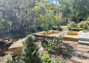 The full garden including the sunken limestone patio, raised mild steel vegetable beds, rectilinear paver paths and new perennial plantings sparkle in the bright sun on a summer day in the Milwaukee Avenue neighborhood.