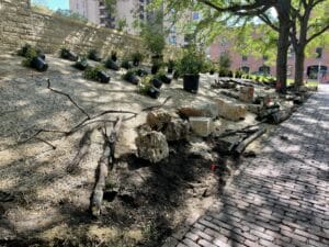 Dozens of limestone boulders and multiple piles of logs are lined up along the long and narrow planting strip, waiting to be installed in the urban pollinator garden.