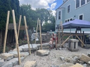 Wooden boards in an a-frame formation act as temporary guides for a in-progress dry-stacked stone wall.
